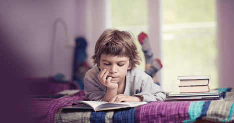 Stock photo image of boy reading a book with his hand on his face. Image links to "Publications" page
